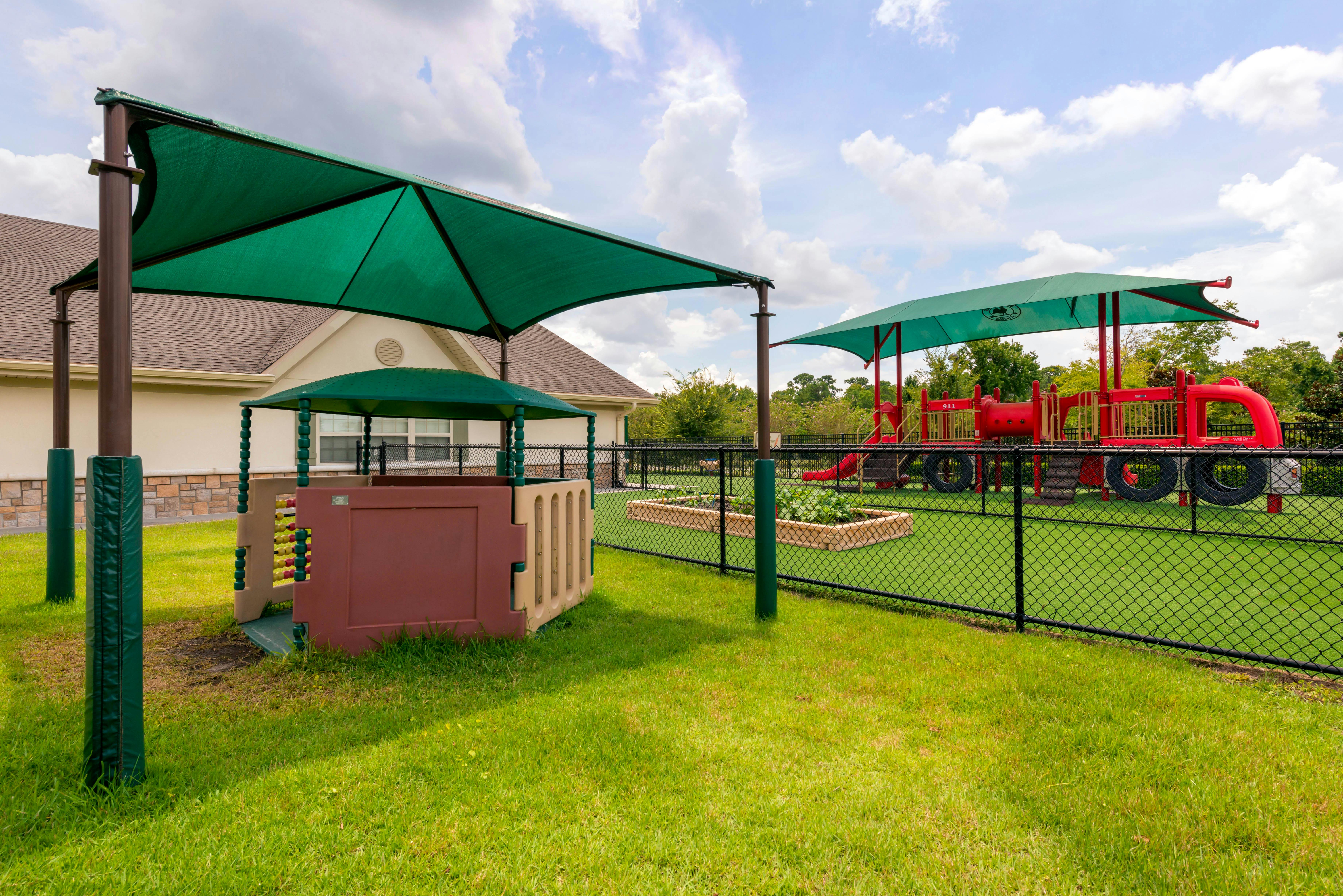 Playground with shade structures and a red play structure shaped like a truck