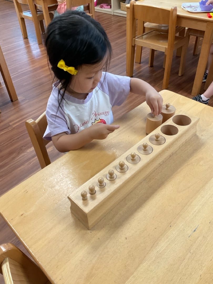 Child playing with wooden cylinder blocks on a table