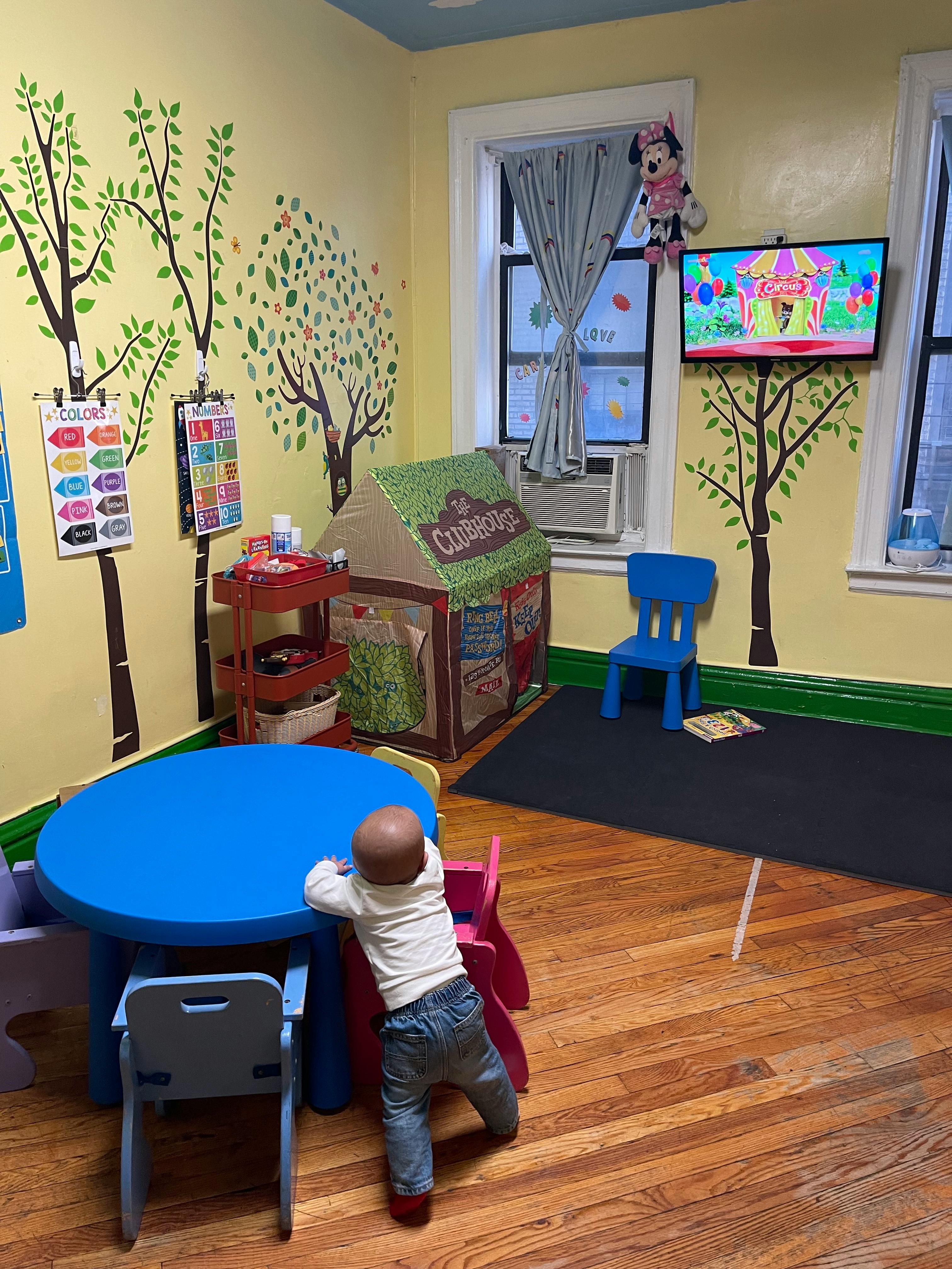 Child standing at a blue table in a playroom