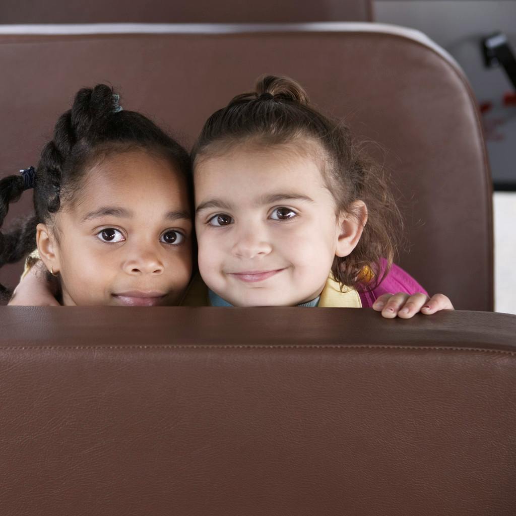 Two children looking over a seat