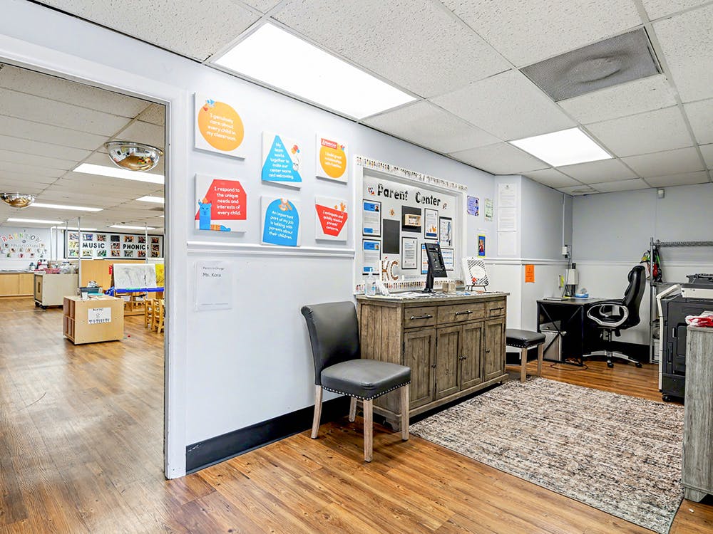 Lobby area with a counter and an open doorway to a classroom with tables and chairs