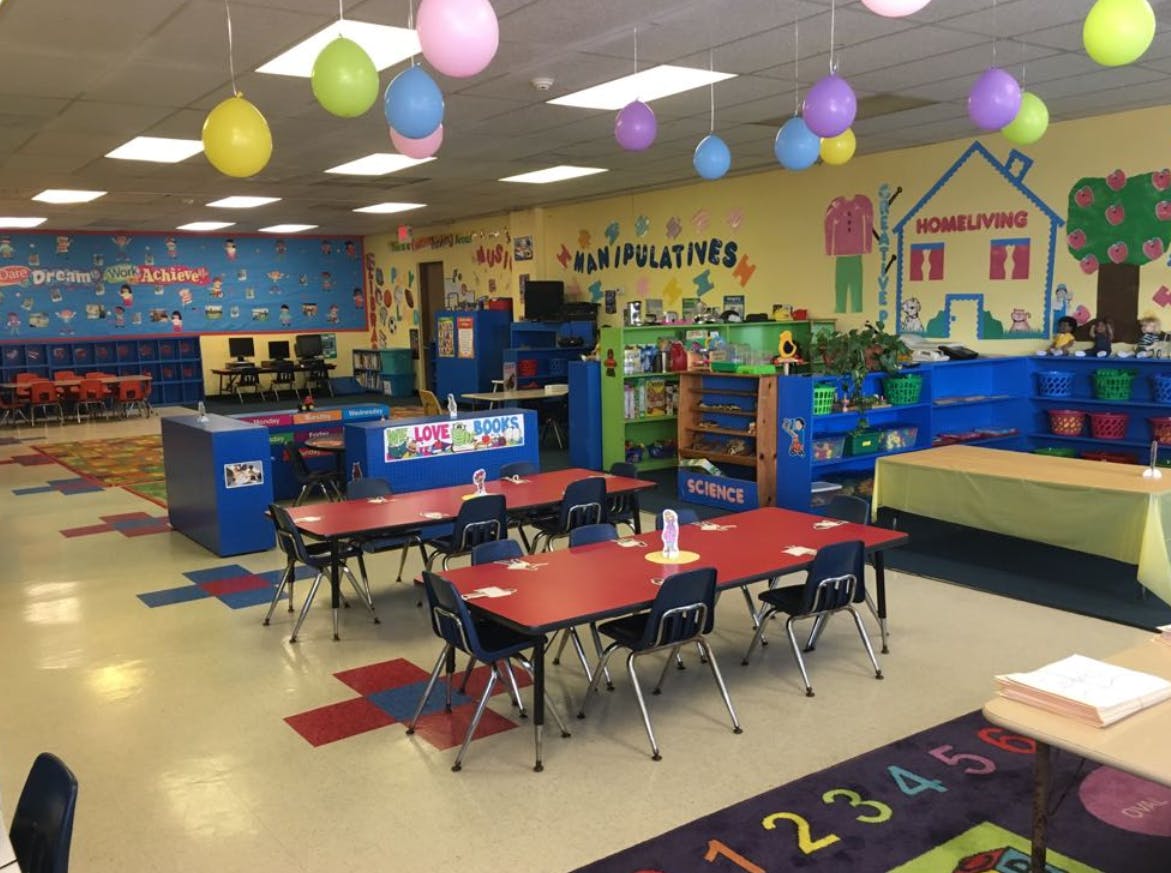Classroom with small tables and chairs, colorful walls, and balloons