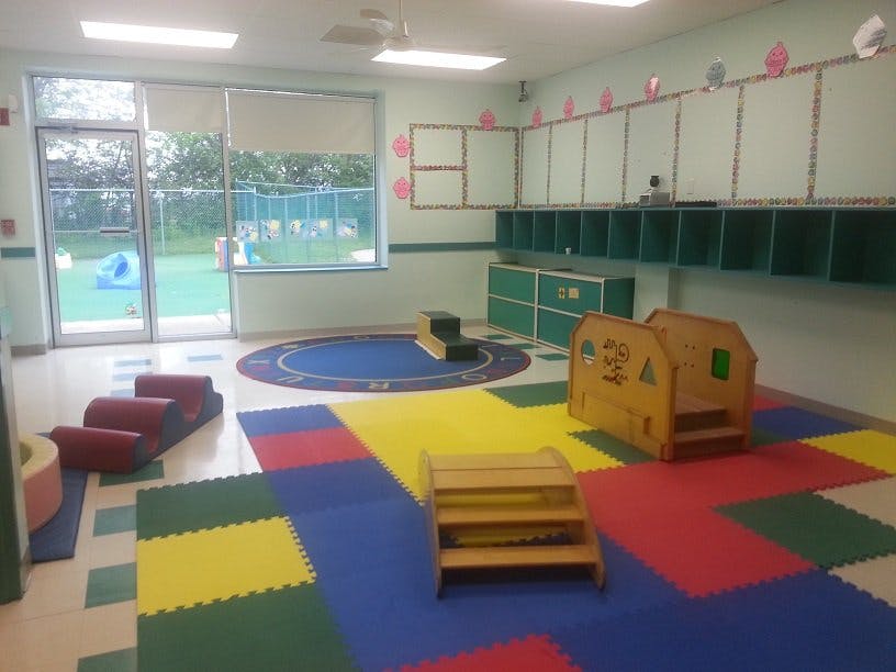 Empty classroom with colorful floor mats and play equipment