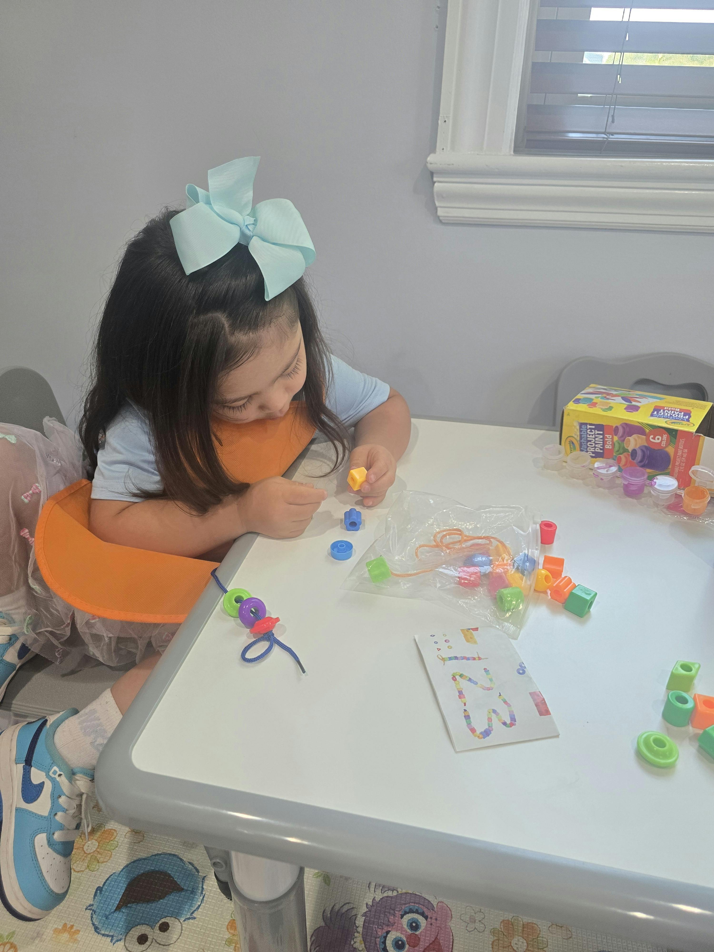 Child stringing plastic beads at a table