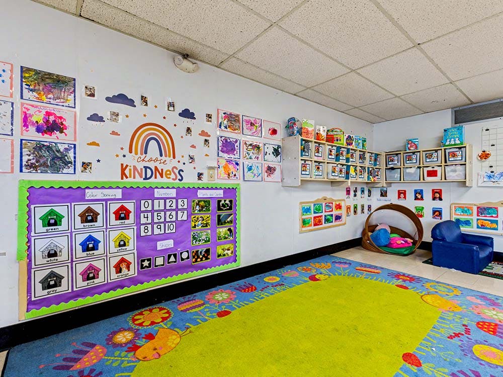 Children's classroom with artwork on walls, a rug, and a reading nook