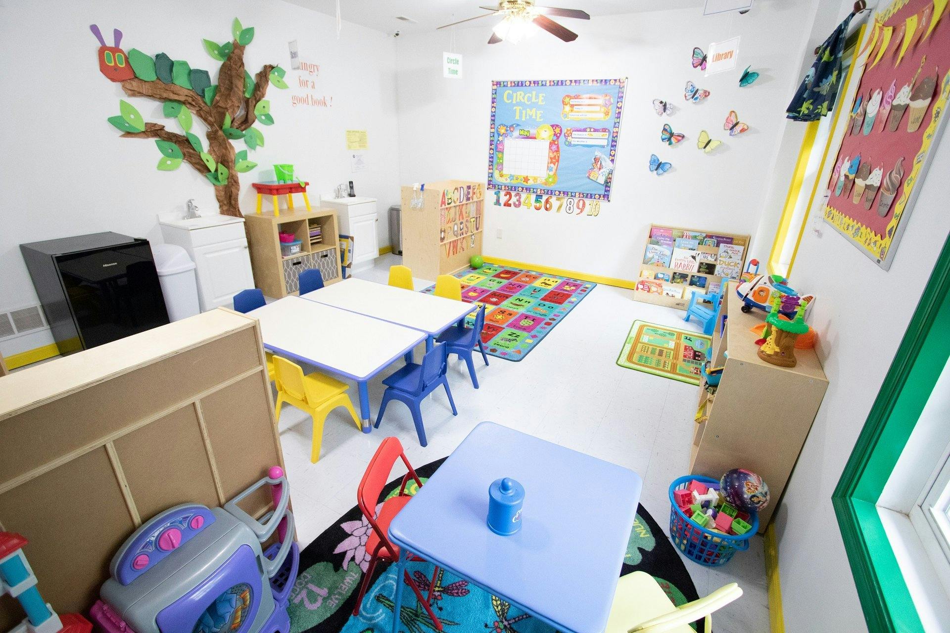 A colorful classroom with small tables, chairs, and play areas