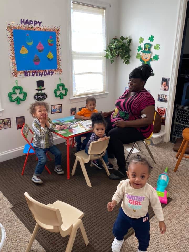 Adult and children in a room with a table, one child standing