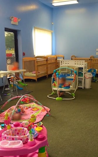 Nursery room with multiple cribs, play mats, and baby bouncers