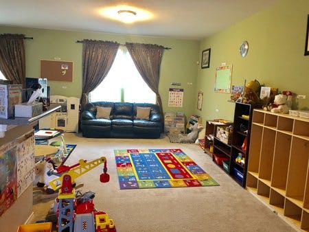 Playroom with a colorful rug, toys, and a black sofa