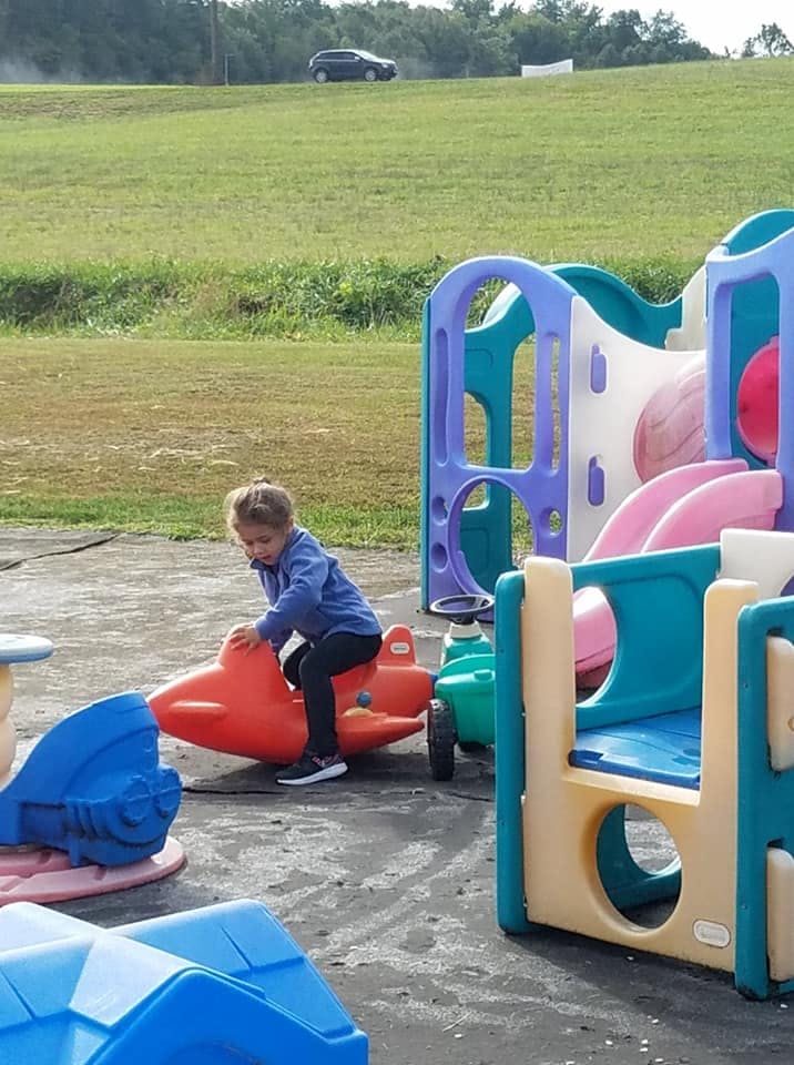 Child on a red airplane ride-on toy at a playground