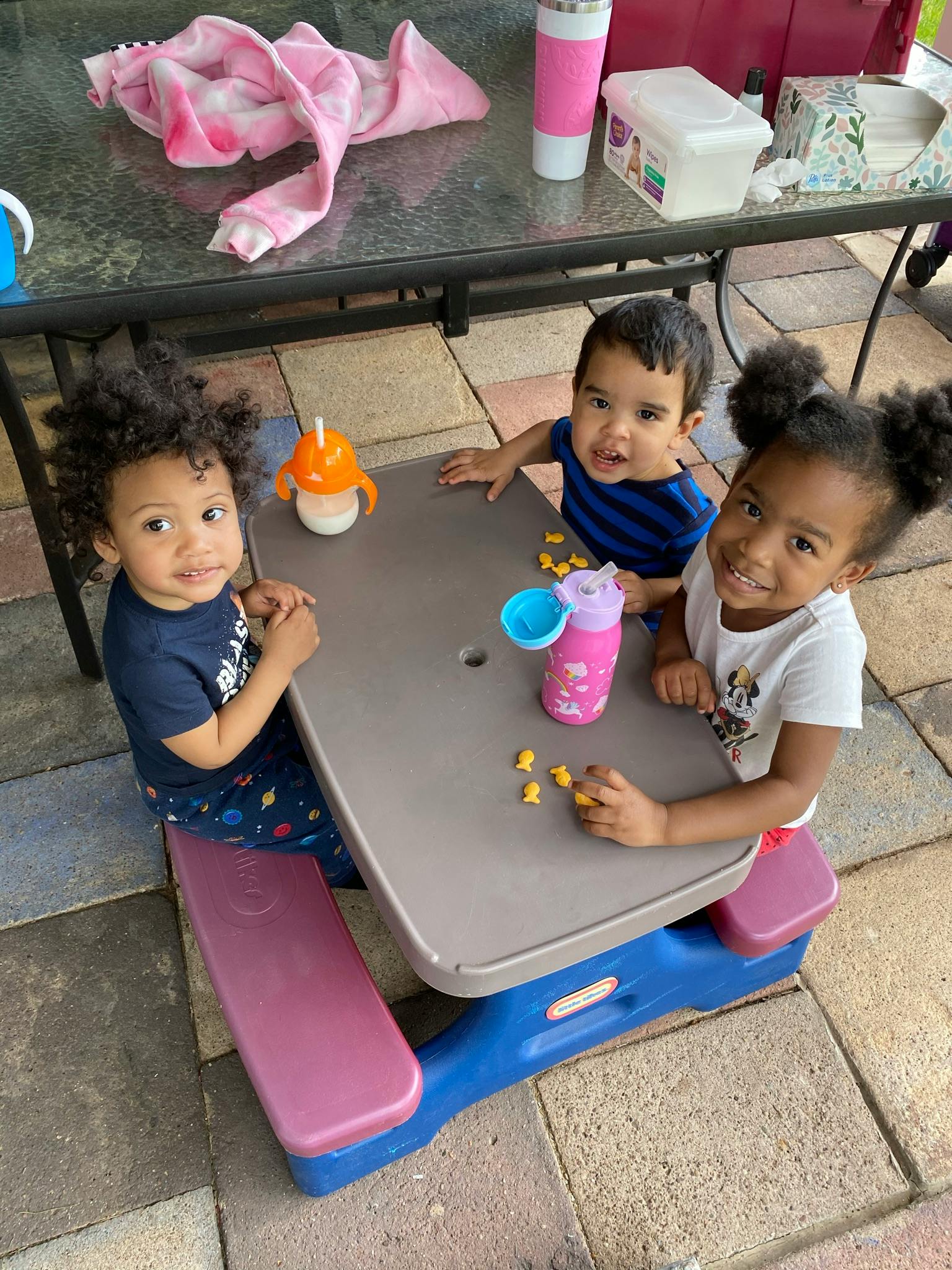 Three children sitting at a small picnic table