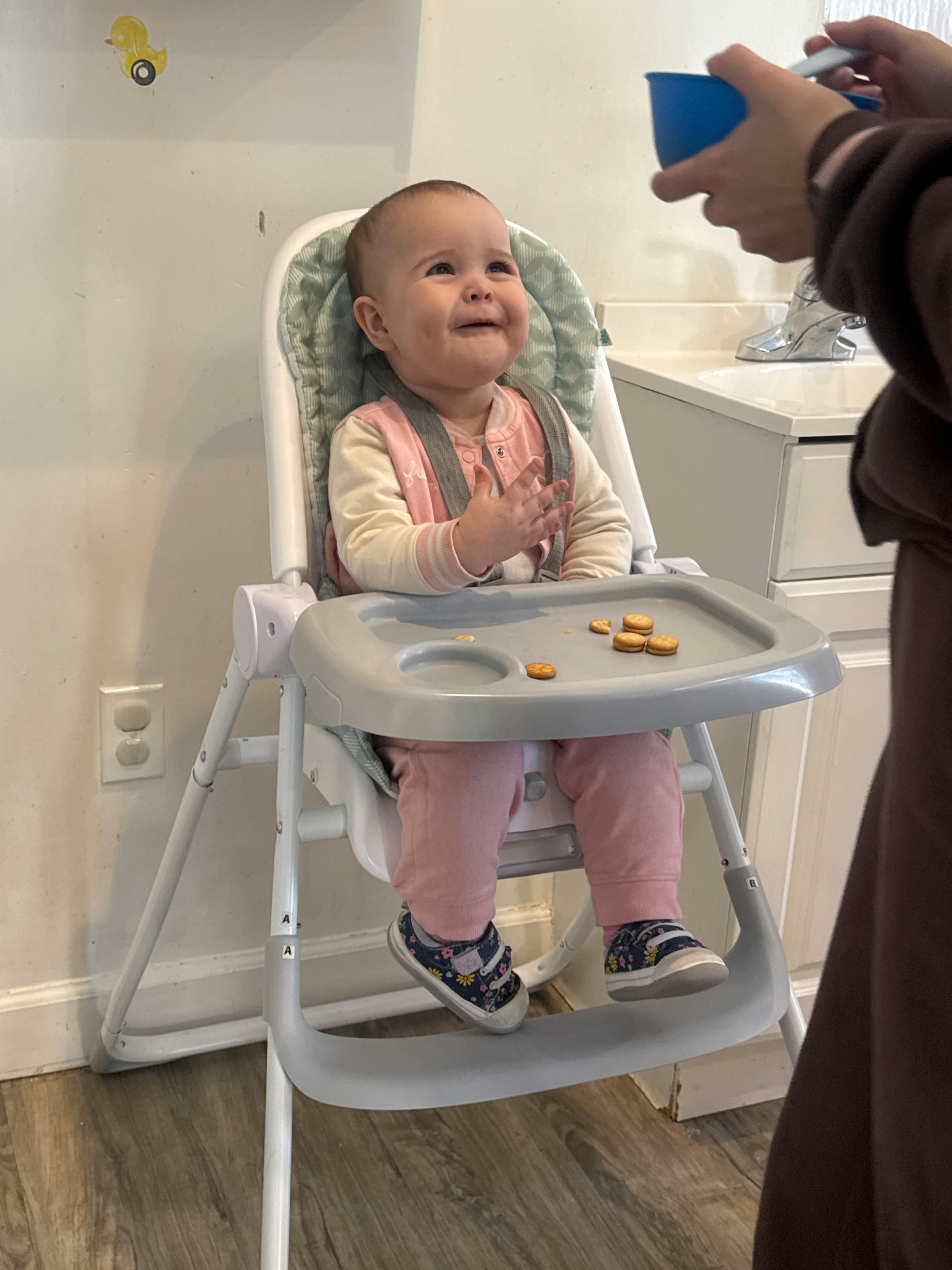 Child in a high chair with crackers on the tray