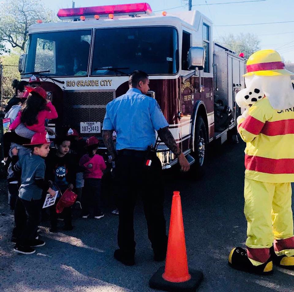 Firefighter and mascot with children in front of a fire truck