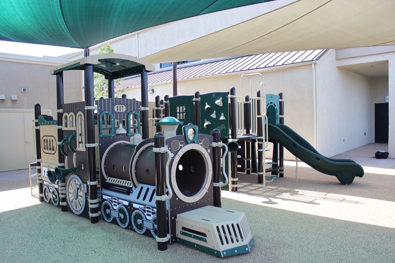 Train-shaped playground structure with a slide in the background