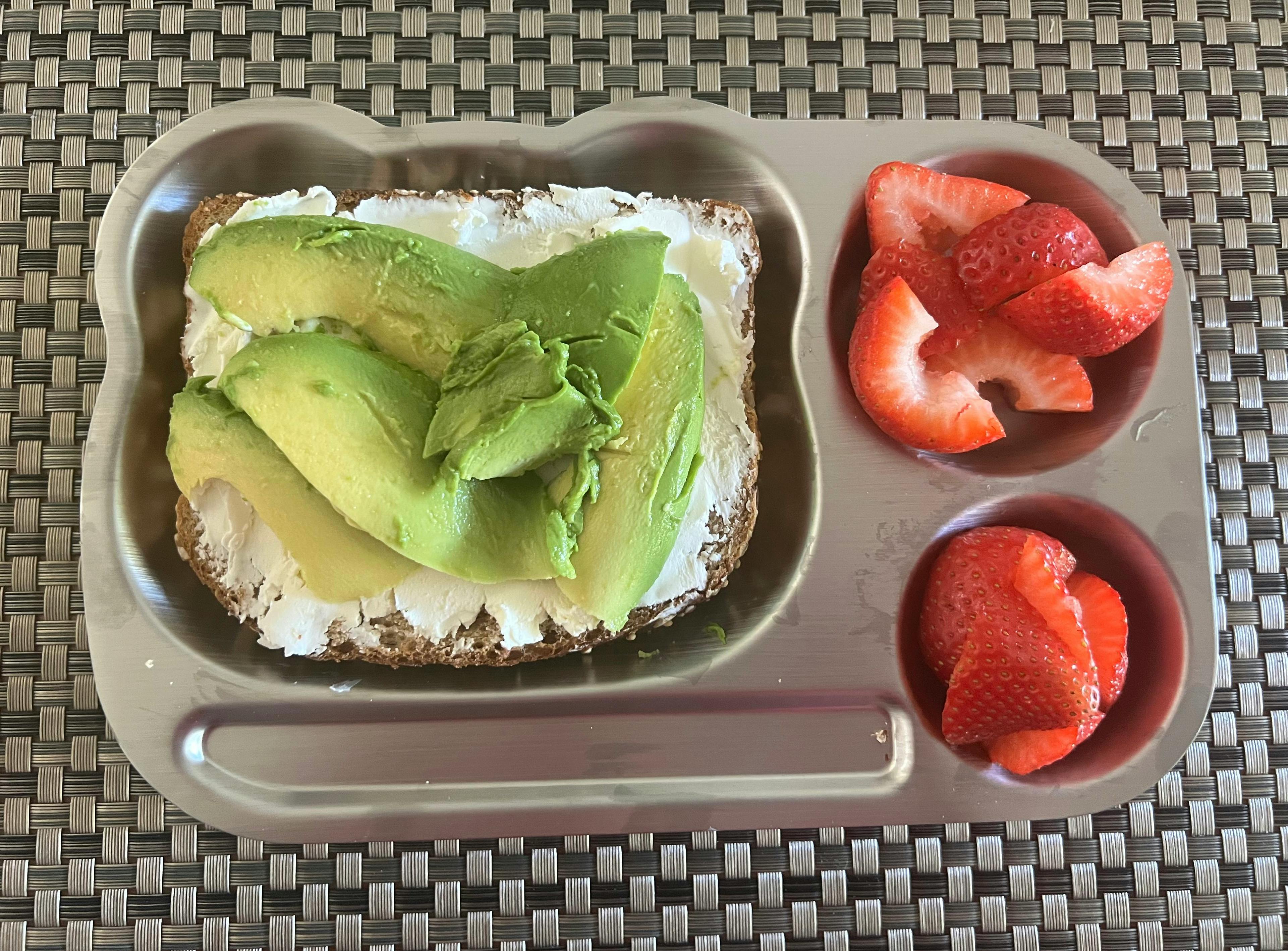 Avocado toast with sliced strawberries in a metal tray