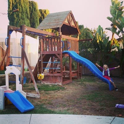 Child on a blue slide in a backyard playground