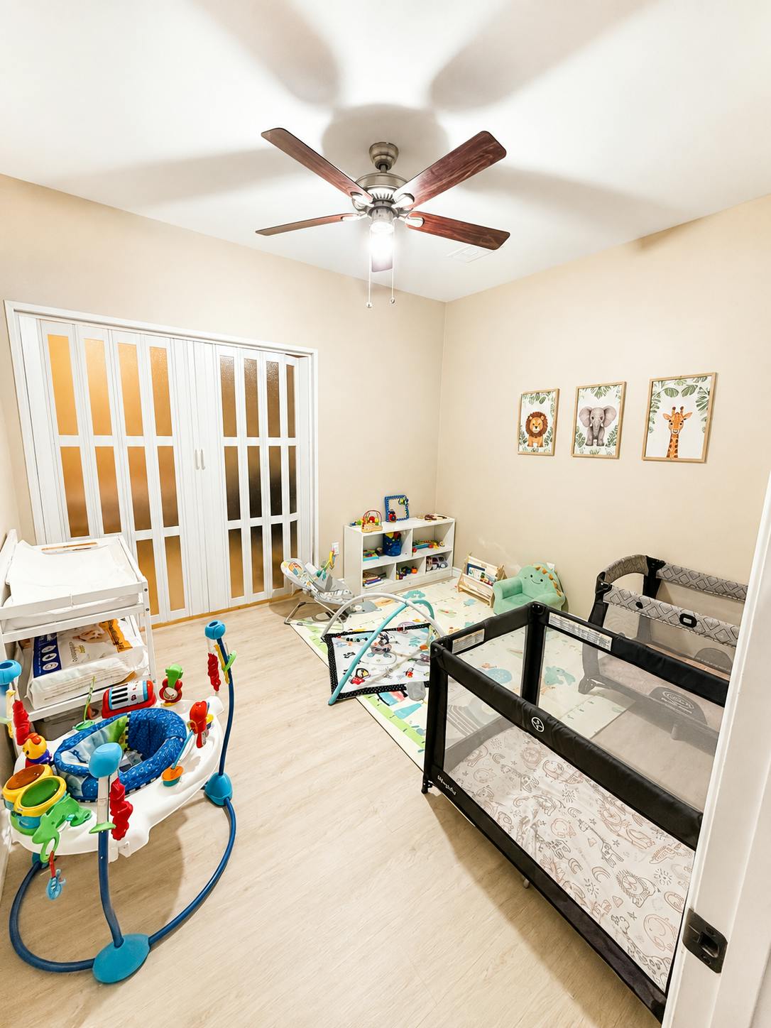 Nursery room with a crib, baby activity center, and play mat on the floor