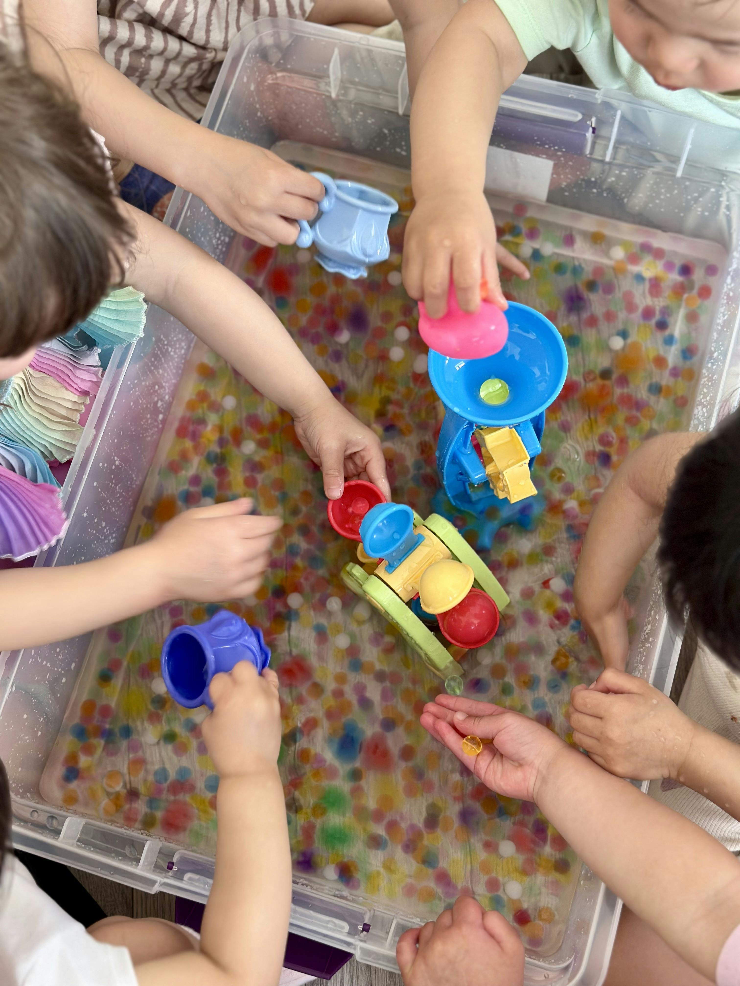 Children playing with water and colorful beads in a sensory bin