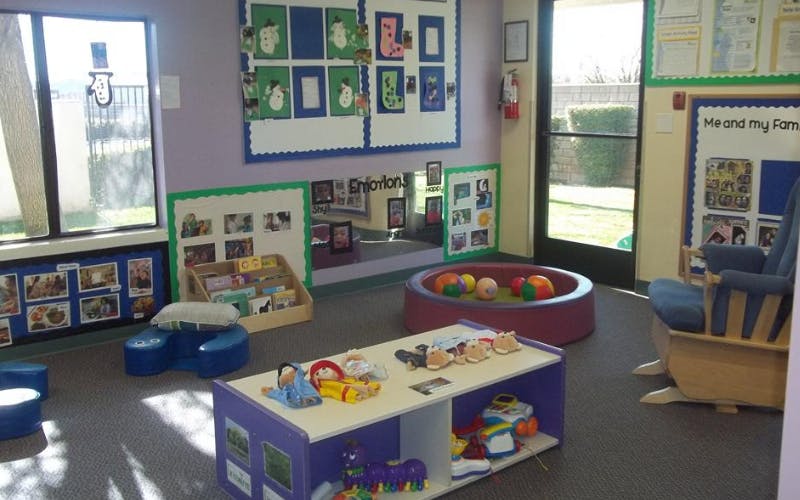 Classroom with child-sized furniture, toys, and educational posters on walls