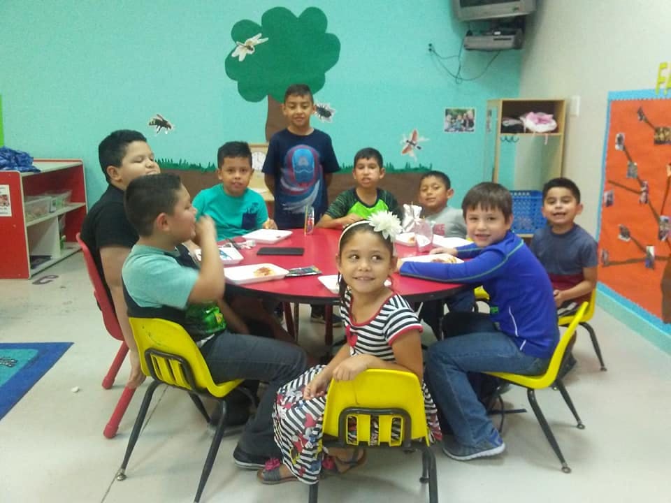 Group of children sitting around a red table in a classroom