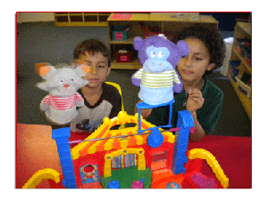 Two children playing with puppets and a toy circus tent