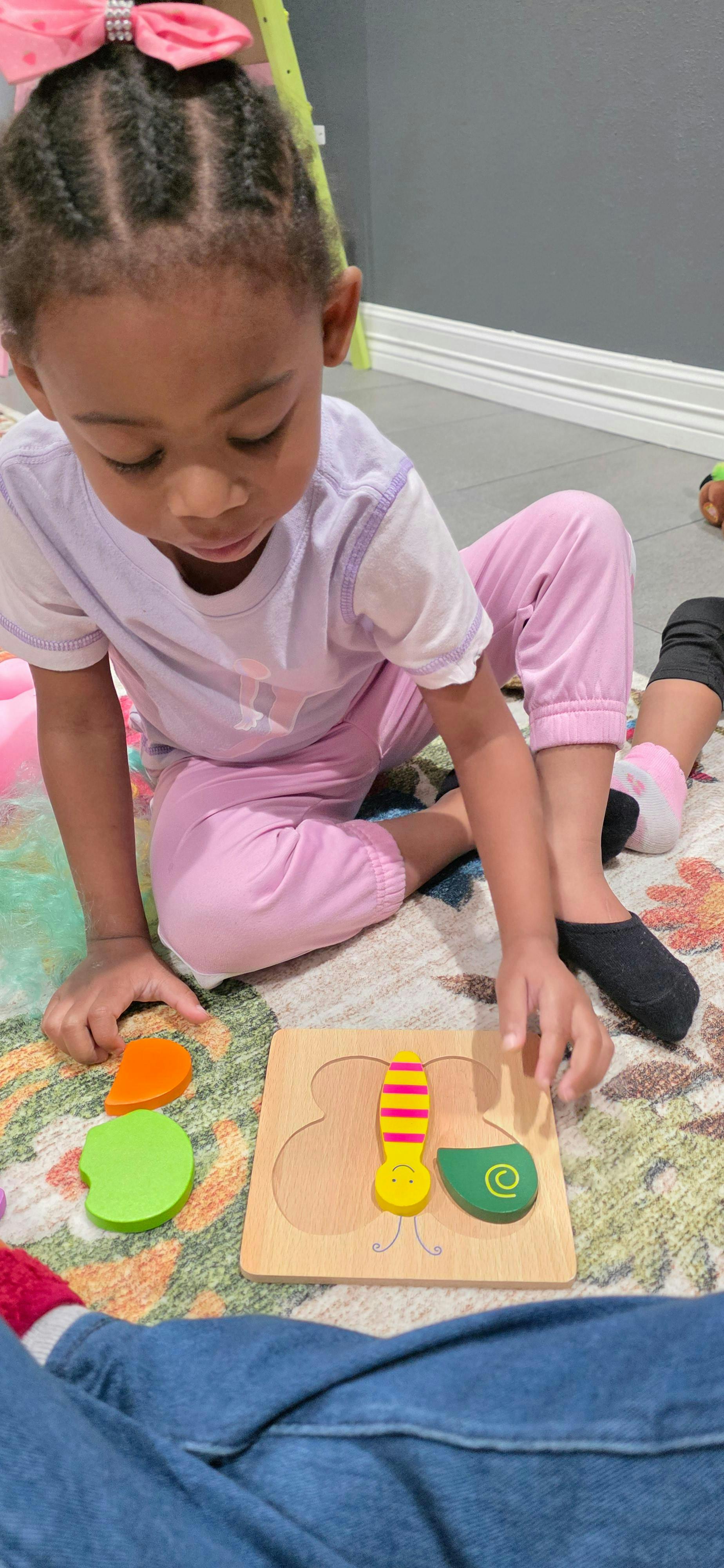 Child playing with a wooden butterfly puzzle on a rug