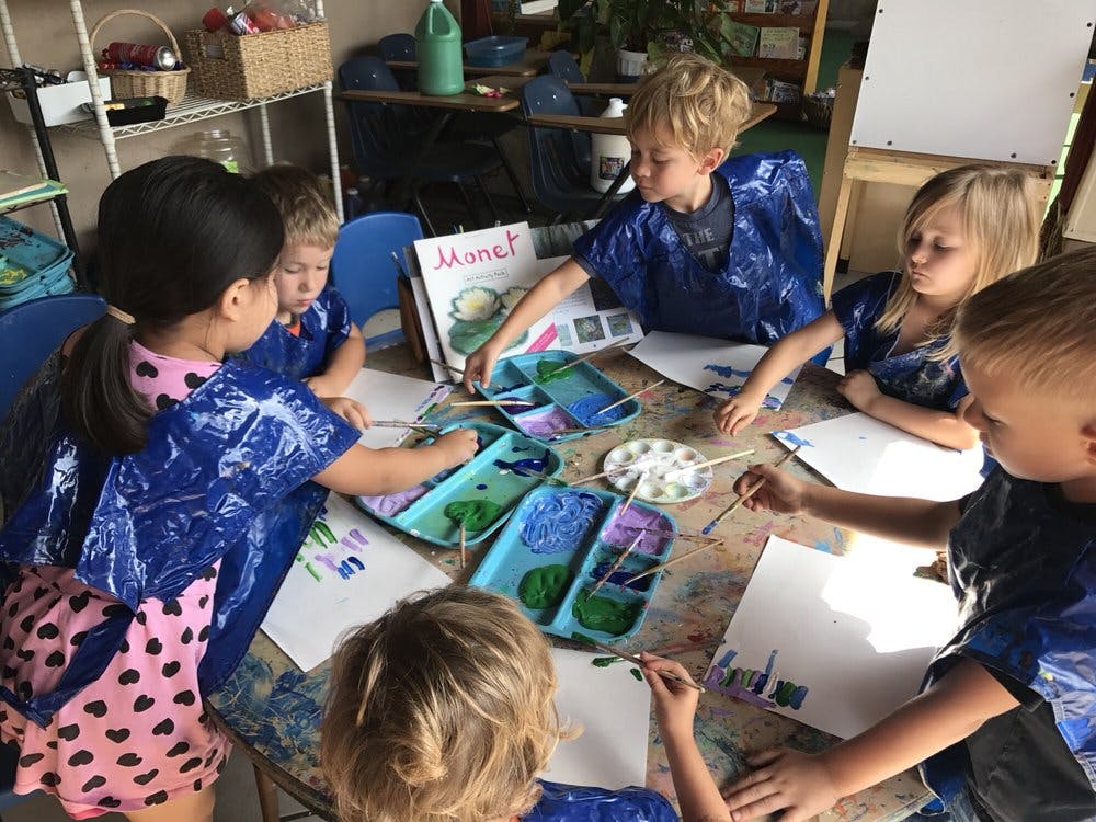 Children painting at a table in a classroom