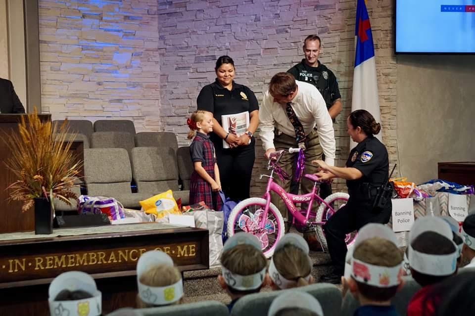 Adults and a child with a pink bicycle on a stage