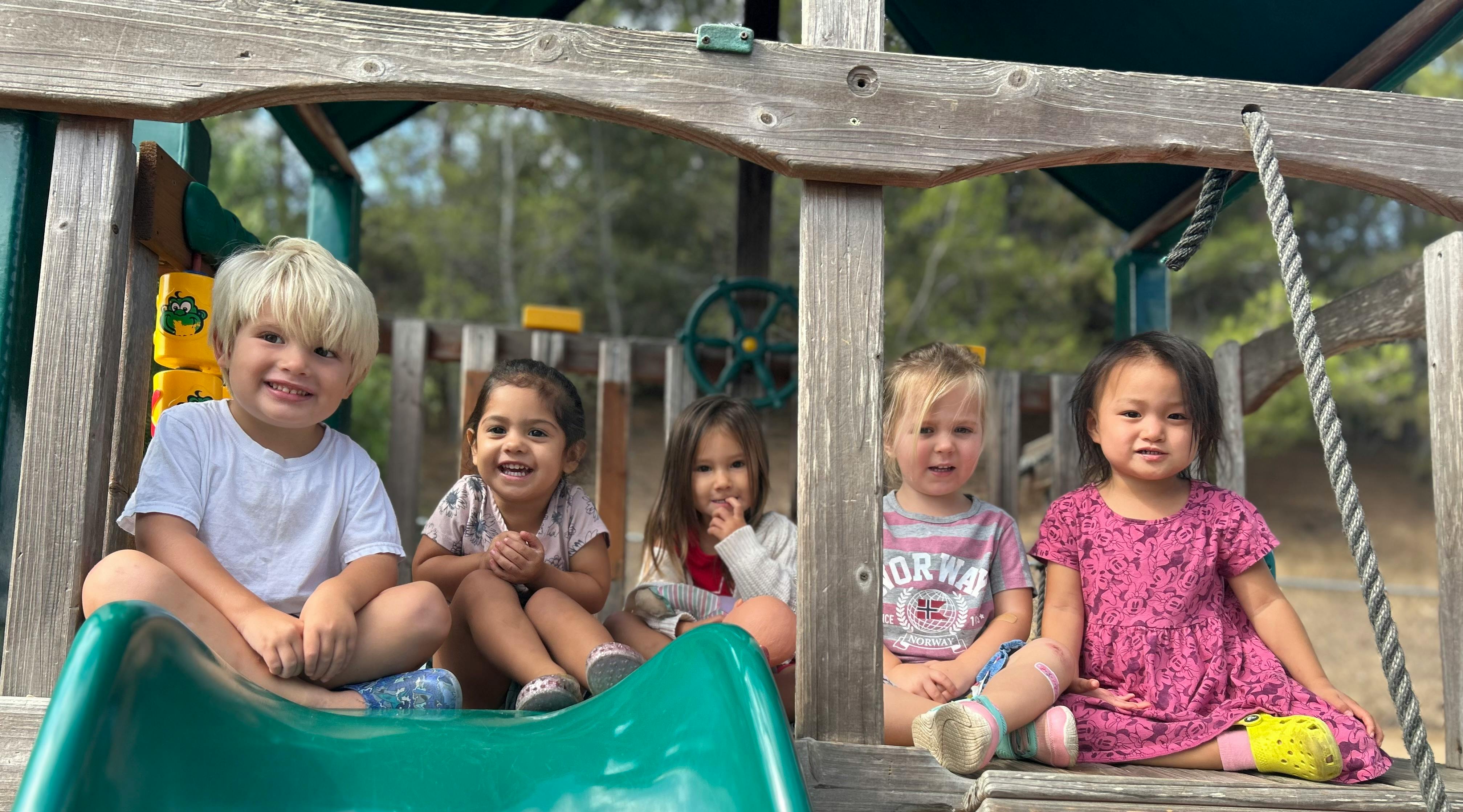 Five children sitting on a playground structure