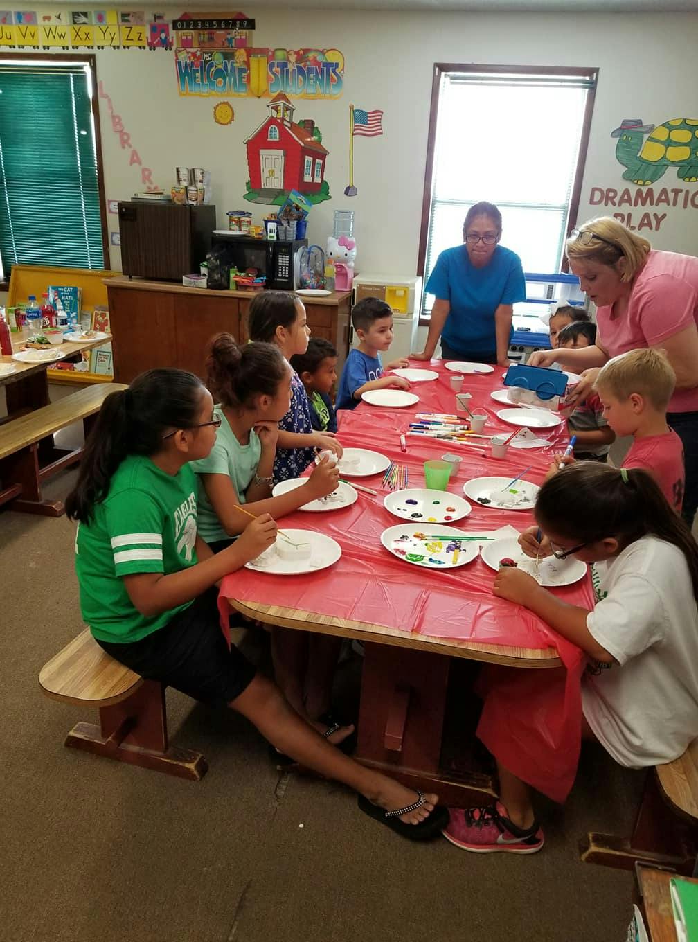 Adults and children sitting around a table with plates of paint