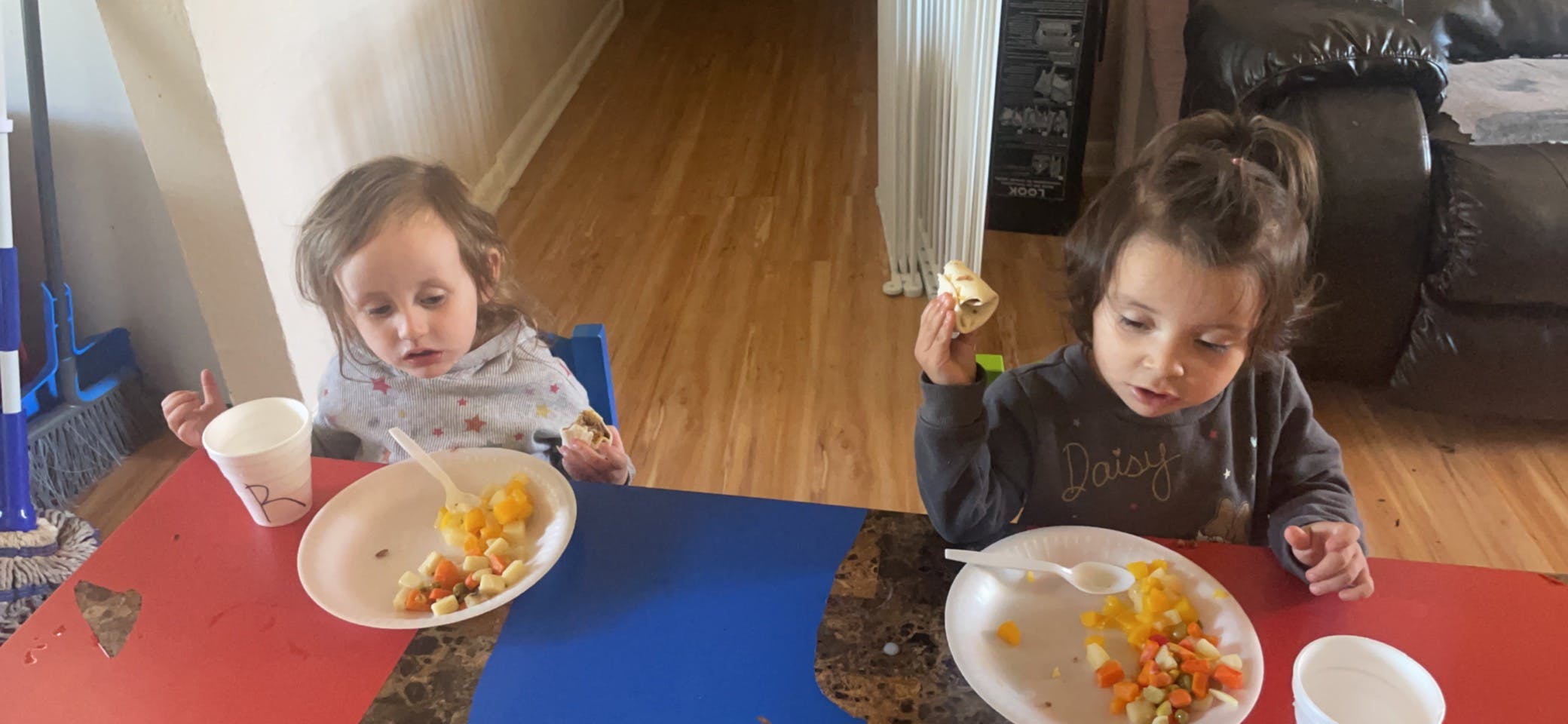 Two children sitting at a table with plates of food