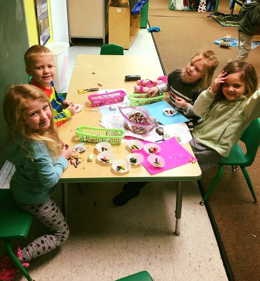 Four children sitting at a table with craft supplies
