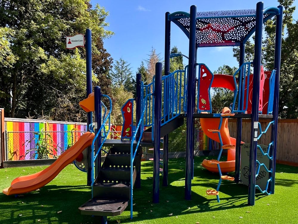 A children's playground with a large blue and orange play structure on green turf