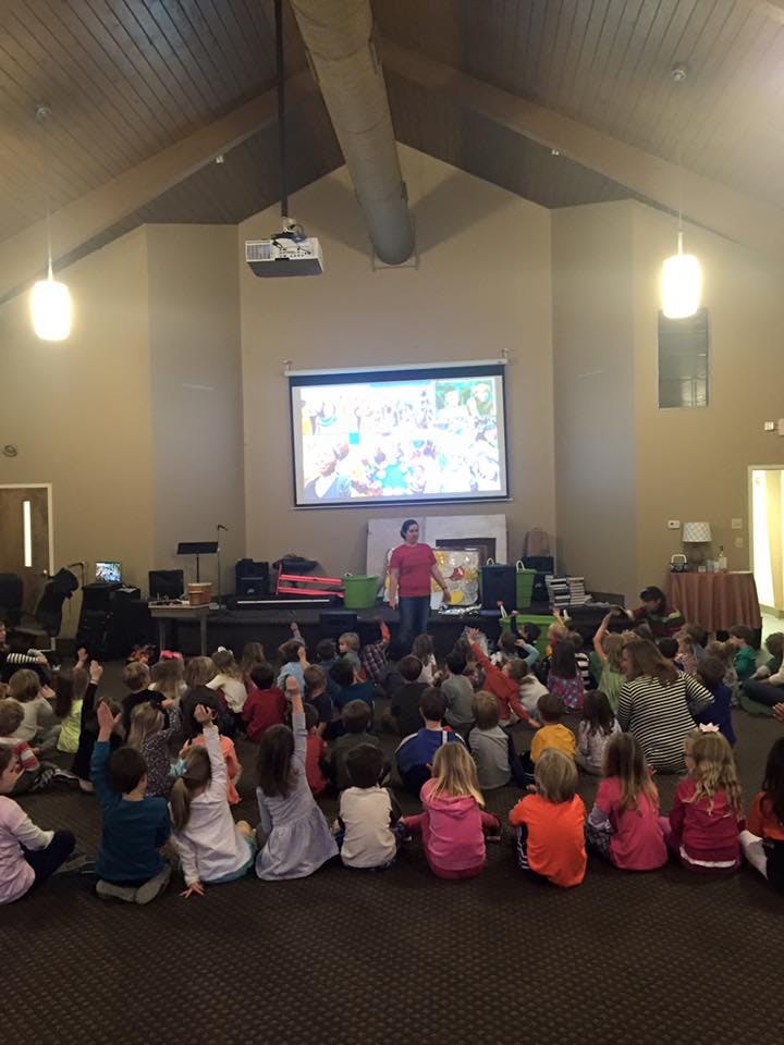 Person speaking to a group of children sitting on the floor