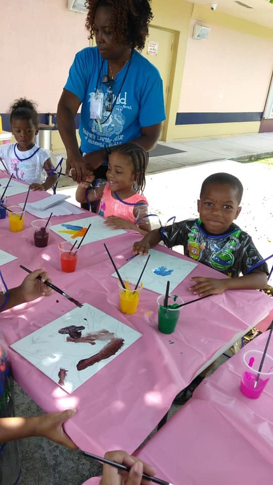Adult supervising children painting at a table