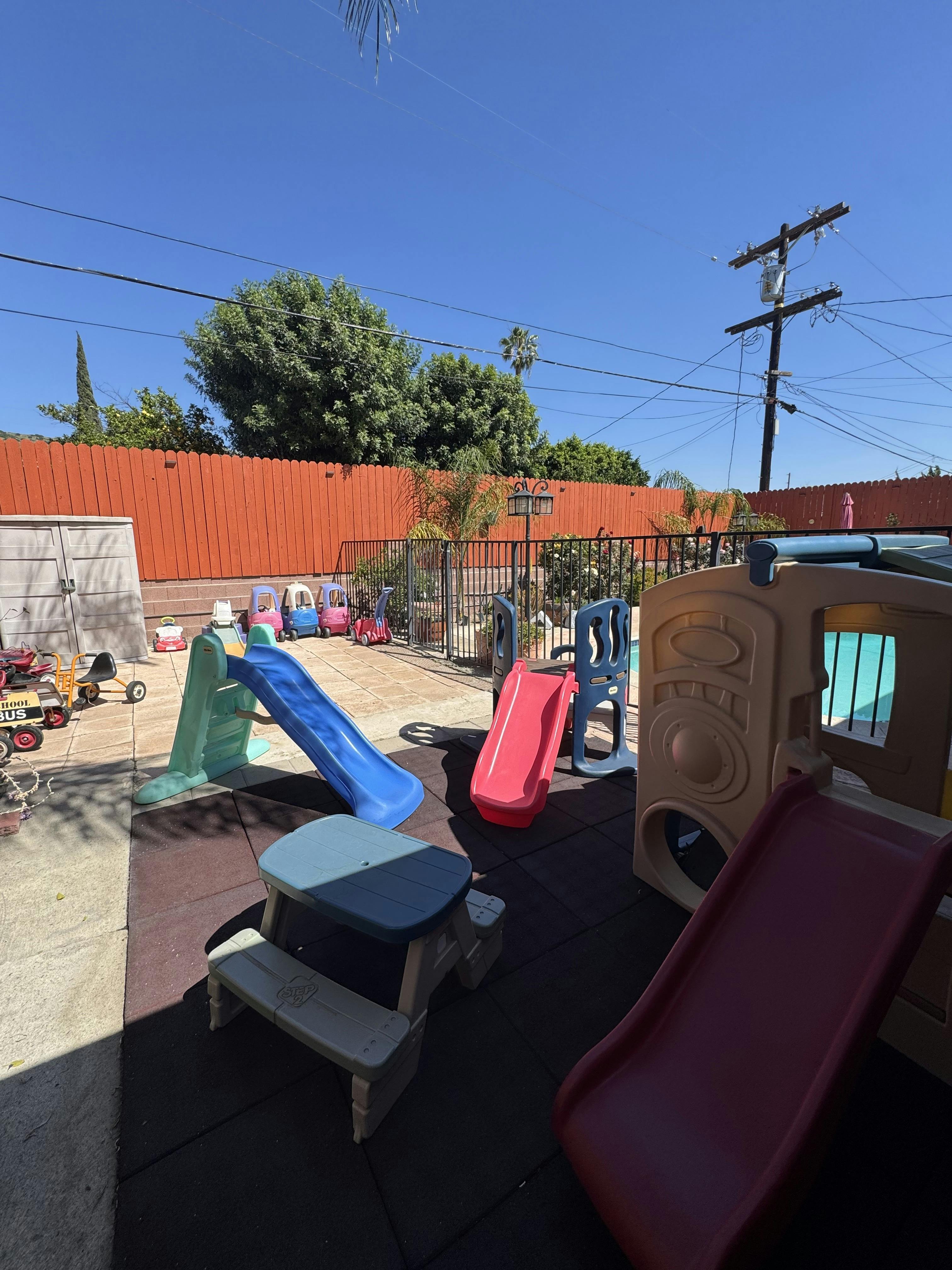 A backyard play area with various slides and ride-on toys