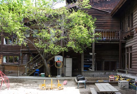 Playground with wooden building, tree, and various play equipment