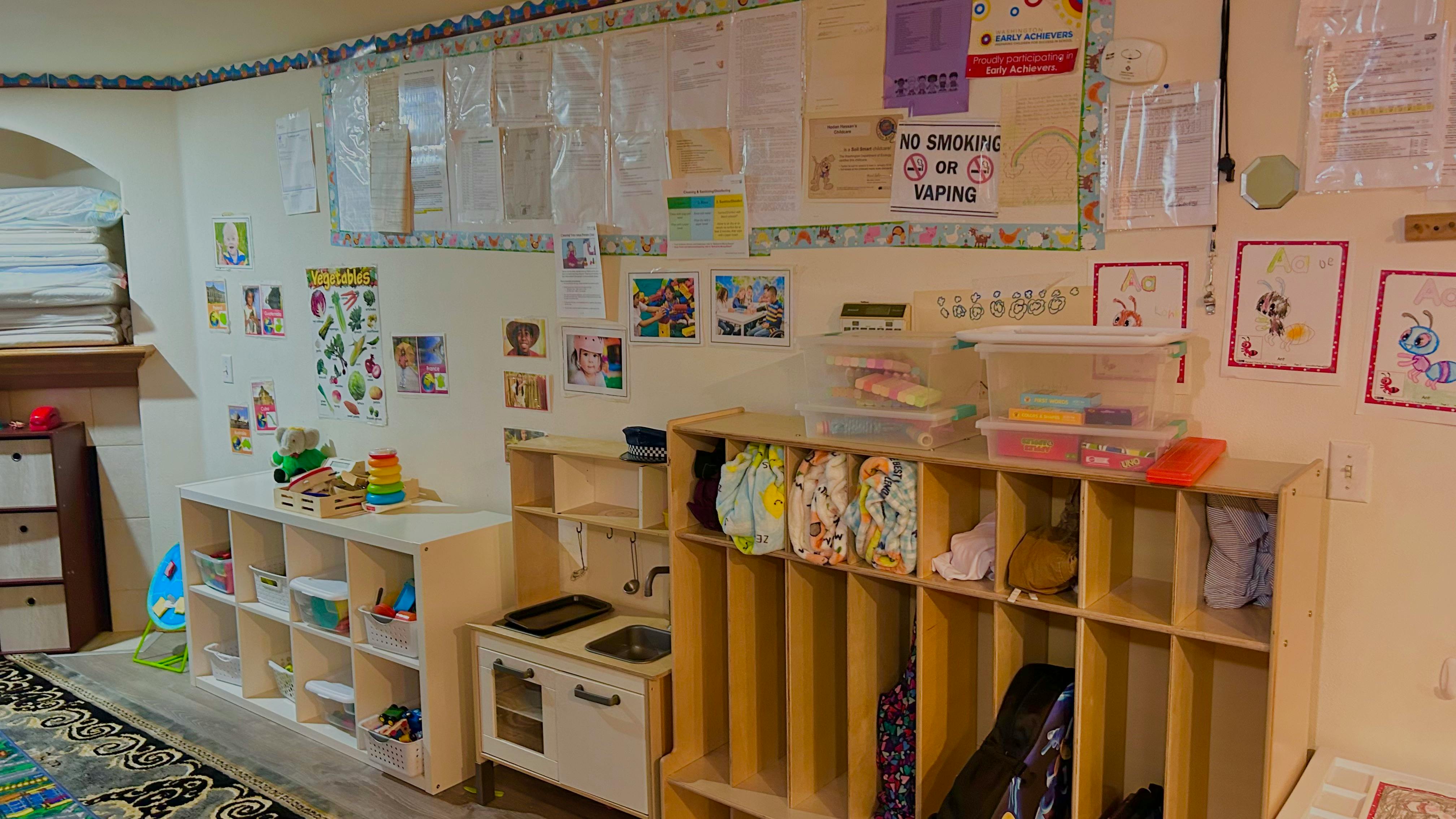 Children's play area with shelves, toys, and artwork on the walls