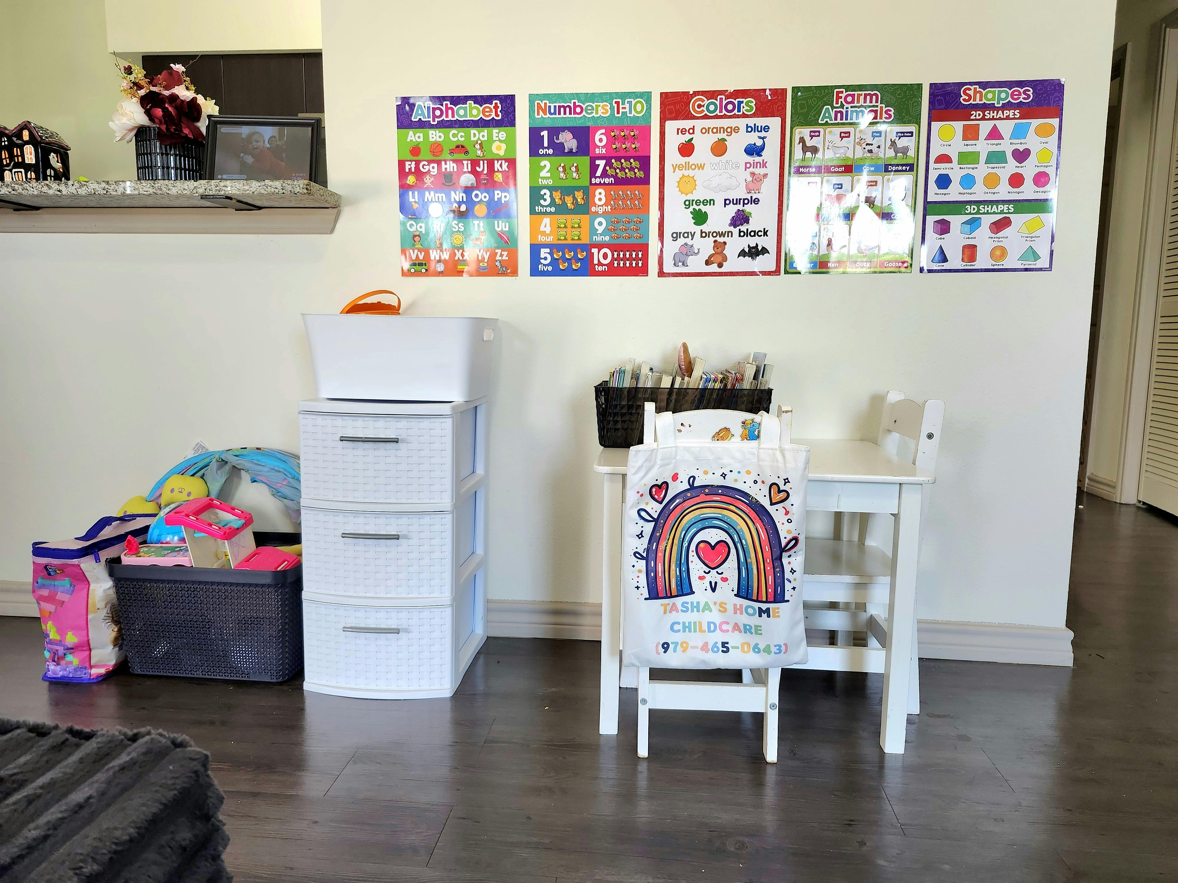 Childcare room with educational posters, a small table, and toy bins
