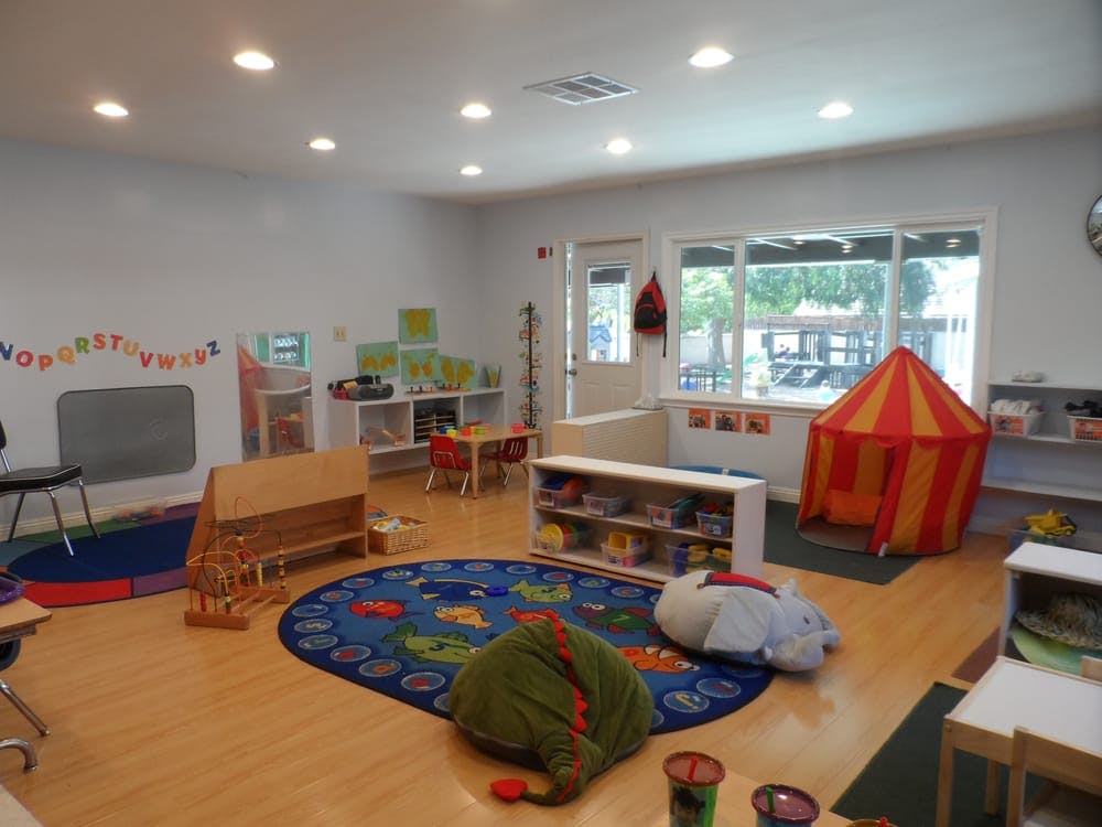 Playroom with a red and yellow tent, blue rug, and small tables