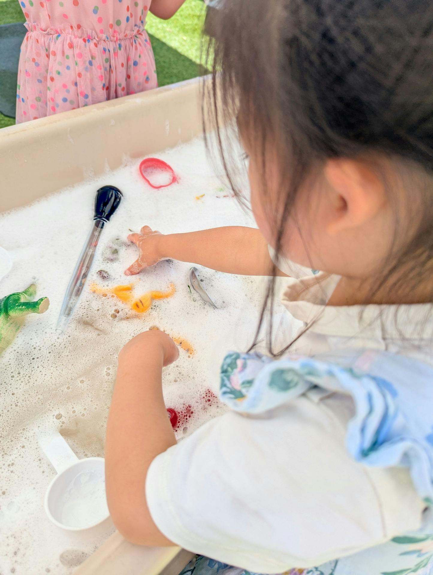 Child playing with toys in a soapy water bin
