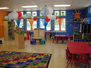 Colorful classroom with tables, chairs, and an alphabet rug