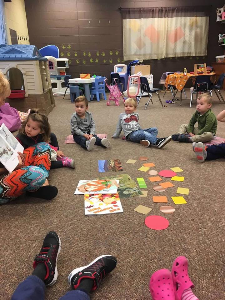 Children sitting on the floor with books and paper shapes