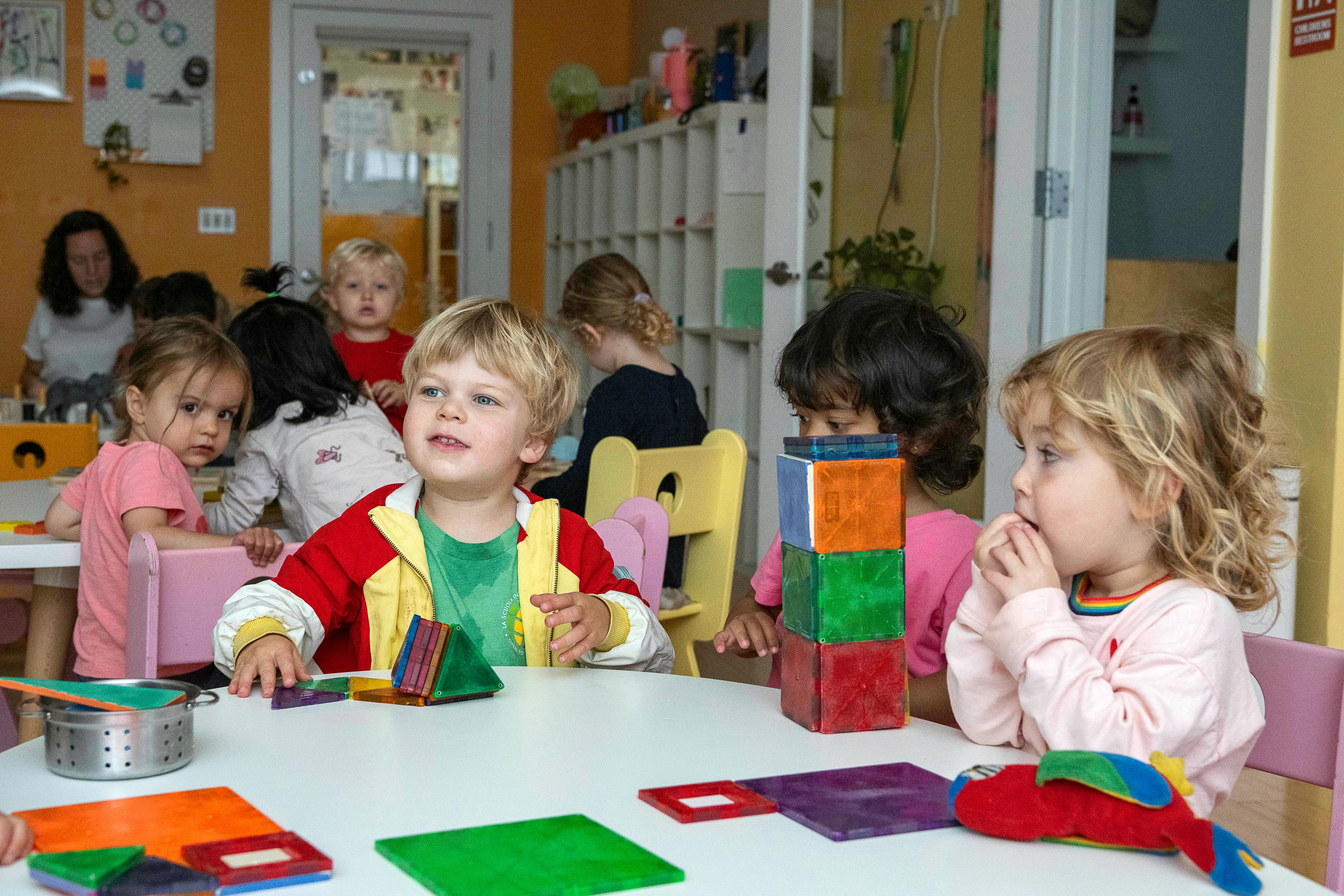 Children playing with blocks at a table in a classroom