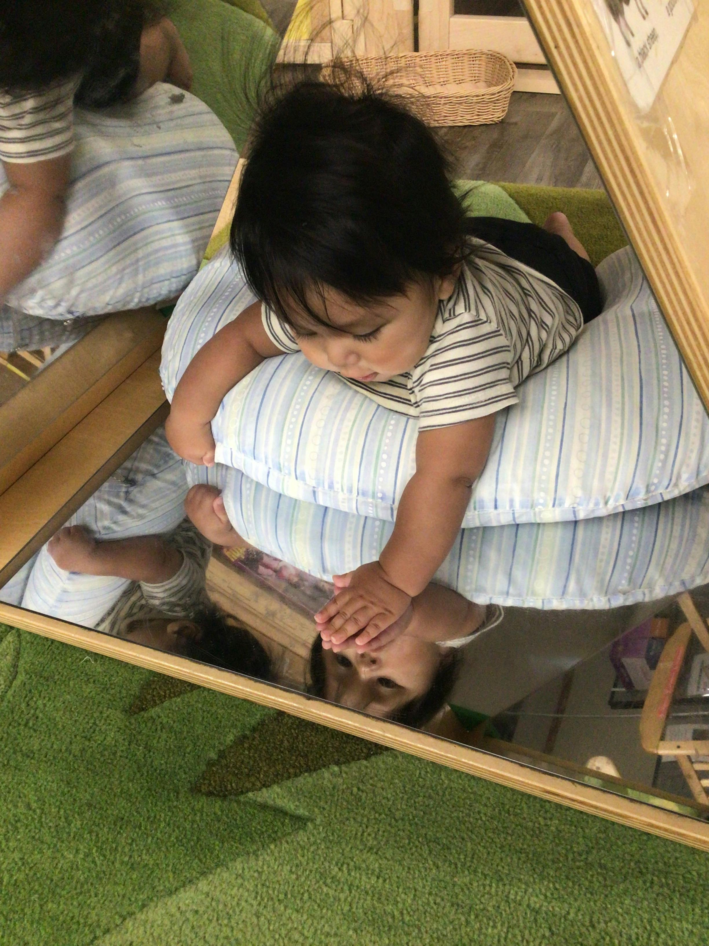 Child on a pillow looking at their reflection in a mirror