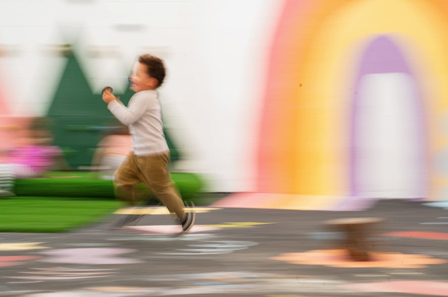 Child running past a colorful mural outdoors