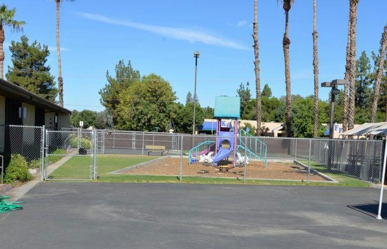 Playground with slides and climbing structures behind a chain link fence