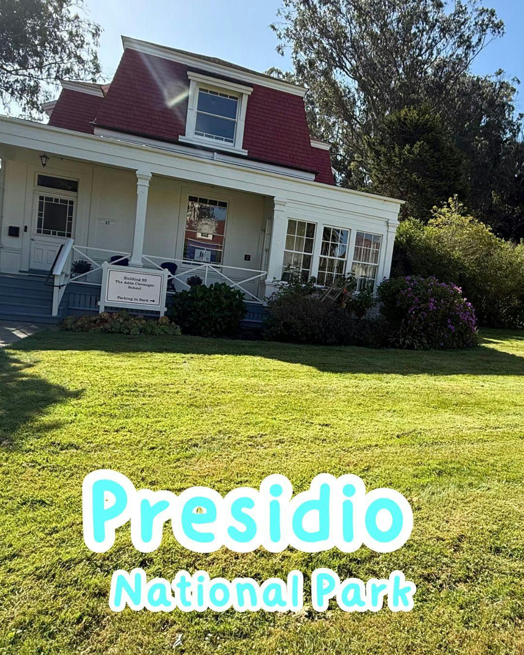 White house with red roof and porch, green lawn in foreground