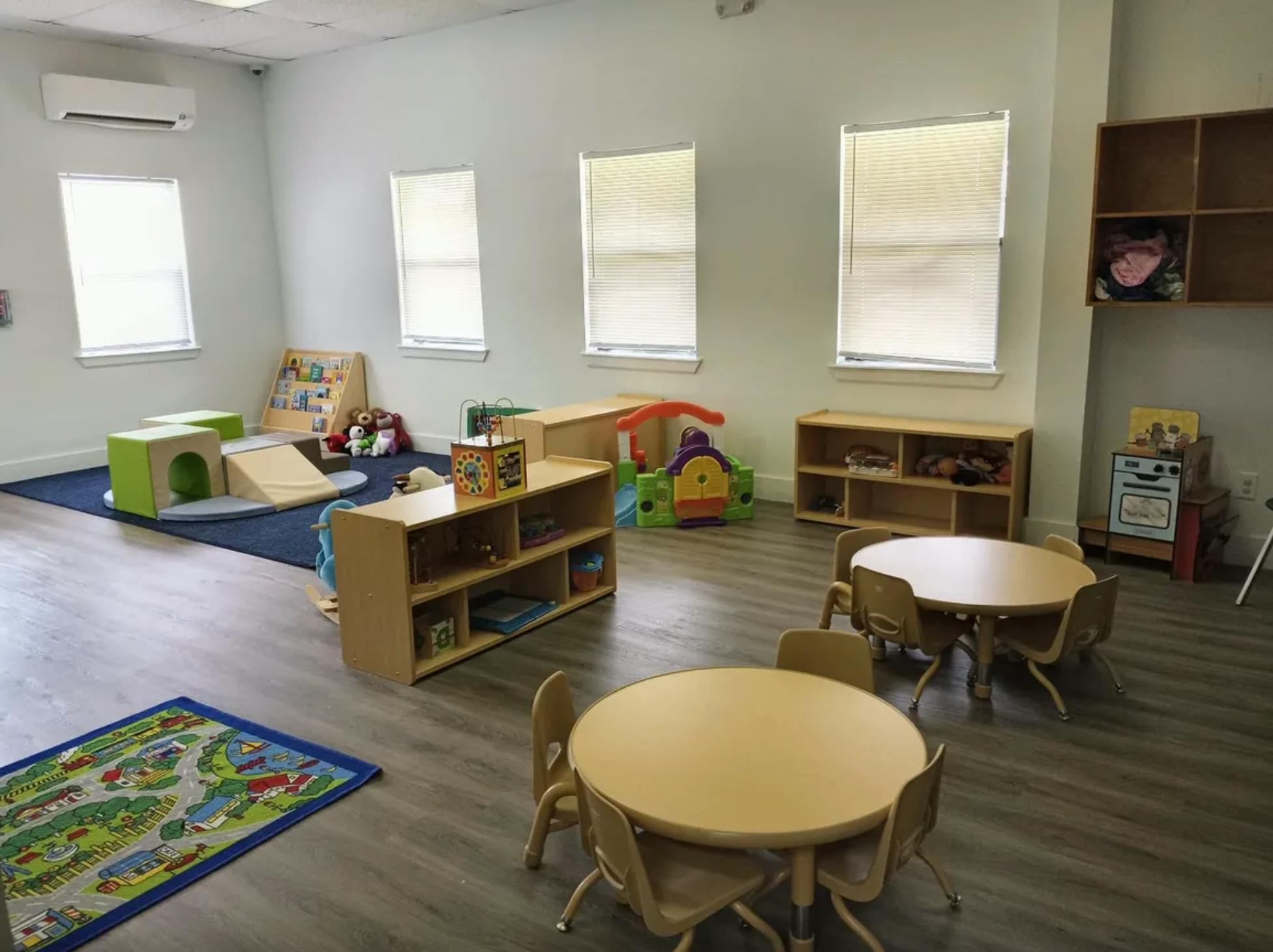 Playroom with small tables and chairs, shelves, and play equipment