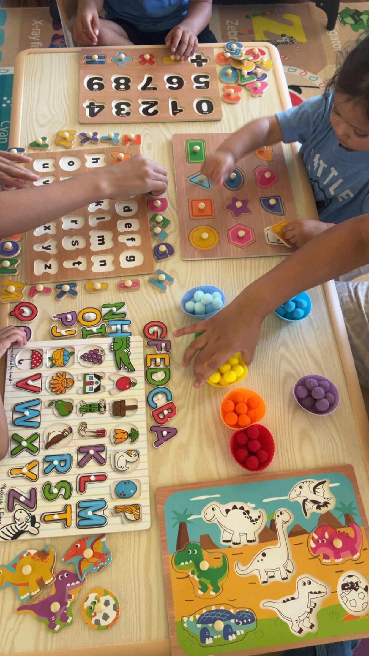 Children learning with educational puzzles and colorful pom-poms